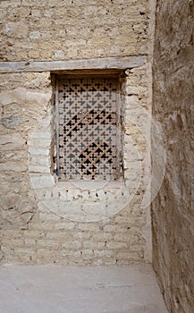 Ancient wooden window with geometrical pattern based on the christian cross on external brick stone wall