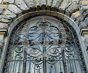 An ancient wrought-iron grille, a decorative security element. An old grille on the window of an old house with beautiful brick wa