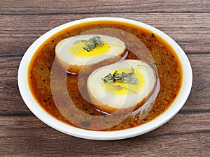 Anda Masala or Egg Curry is popular indian spicy food, served in a ceramic bowl over rustic wooden background. Selective focus