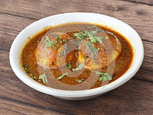 Anda Masala or Egg Curry is popular indian spicy food, served in a ceramic bowl over rustic wooden background. Selective focus