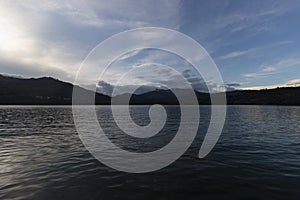 Andean mountain range blue sunset viewed from a lake shore with watter reflection