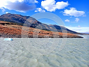 Andes mountains with cloudy waters and waves with ice blocks under blue sky of Patagonia Argentina. Nature and extreme landscapes