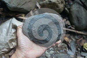 Hand is holding a raw specimen of andesite extrusive igneous rock. photo