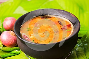 south indian famous rasam,sambar served in a traditional mud pot closeup with selective focus and bl photo