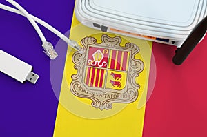 Andorra flag depicted on table with internet rj45 cable, wireless usb wifi adapter and router. Internet connection concept