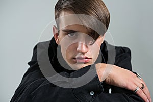 Androgynous man in black shirt posing against grey background