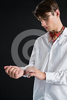 Androgynous man buttoning his shirt sleeve