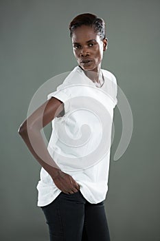 Androgynous man in white top posing against grey background