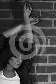 Androgyny female model in Heroin chic style near brick wall.