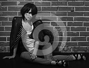 Androgyny female model in Heroin chic style near brick wall.