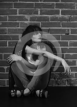 Androgyny female model in Heroin chic style near brick wall.