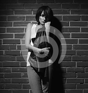 Androgyny female model in Heroin chic style near brick wall.