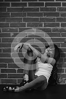 Androgyny female model in Heroin chic style near brick wall.