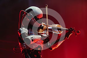 An android robot playing a violin at an orchestral classical music concert performing as part of the orchestra photo