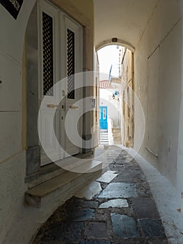 Andros island Chora, Cyclades Greece. Whitewashed walls, paved alley, house background. Vertical