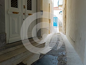 Andros island Chora town, Cyclades Greece. Whitewashed walls, paved alley, house background