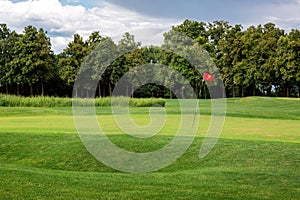 Andscape of a golf course with a green lawn and a hilly surface.