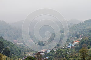 Andscape view of mist-covered village in the mountains in the background.