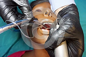 Anesthesiologist in a black gloves performing an orotracheal intubation on a simulation mannequin dummy during medical training