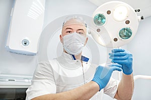An anesthetist doctor holds a syringe in his hands and looks into the frame