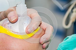 Anesthetist at an operating room holding an oxygen mask on patient face