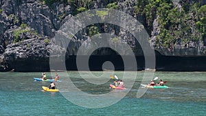 ANG THONG MARINE PARK, SAMUI, THAILAND - 9 JUNE 2019: People kayaking near cliff in paradise sea. Group of tourists paddling while