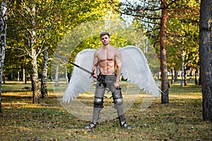 Angel, a bodybuilder in plate armor on his legs with wings behind his back, holds in his hands a two-handed sword