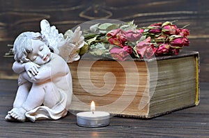 Angel, candle and dry flowers on wooden background