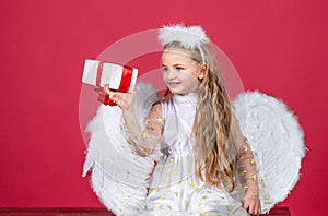 Angel children girl with white wings. Playful angelic little girl with angel wings. Angel kids with present gift, studio