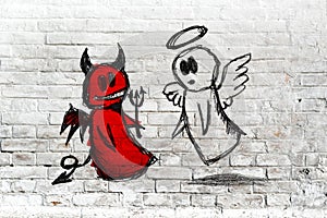 Angel and devil fighting; doodle drawing on white brick wall