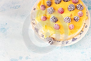 Angel food cake with lemon curd and frozen berries raspberry and blackberry on a plate, blue concrete background.