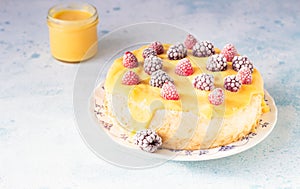 Angel food cake with lemon curd and frozen berries raspberry and blackberry on a plate, blue concrete background.