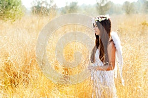 Angel girl in golden field with white wings