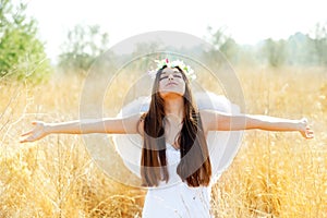 Angel girl in golden field with white wings