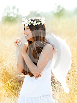 Angel girl in golden field with white wings