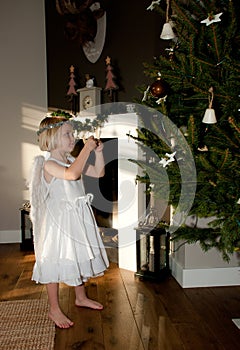 Angel girl with teddy bear before christmas tree