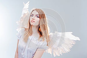 An angel from heaven. Young, wonderful blonde girl in the image of an angel with white wings.