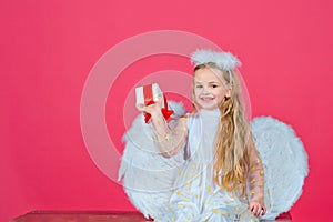 Angel kids, happy fairy with present gift, studio portrait. Little blonde angel with white wings holds gift. Cute angel