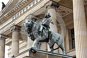 Angel with musical instruments mounting a lion, bronze sculpture, on steps of the Concert Hall, Berlin, Germany