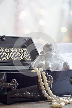 Angel and Pearls necklace in black casket on colorful background bokeh