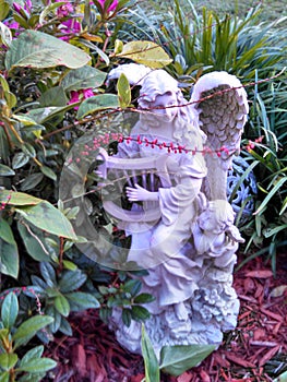 Angel playing harp in a garden