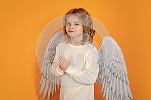 Angel prayer kids. Kid wearing angel costume white dress and feather wings. Innocent child.