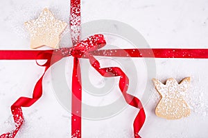 Angel and Star shortbread on marble pastry board wrapped in red ribbon dusted with confectioners sugar