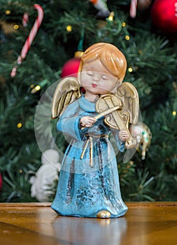 Angel statue playing violin by a Christmas tree