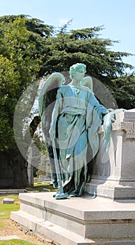 Angel Statue standing beside a funeral crypt