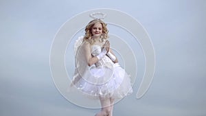 Angel wings baby pray. Love concept. Cute teen cupid on the cloud - heaven background. Angel child girl with curly