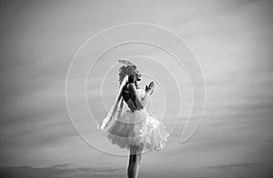 Angel wings baby pray. Love concept. Cute teen cupid on the cloud - heaven background. Angel child girl with curly