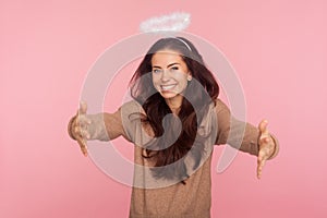 Angelic kindness and generosity. Portrait of beautiful young woman with halo above head holding outstretched hands