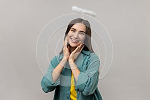 Angelic woman with nimb over head, looking at camera with dreamy facial expression.