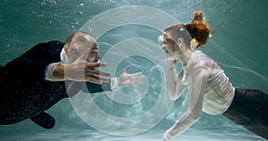 ANGER MANAGEMENT Cinematic underwater shot of young angry businessman and woman argue shout at each other slow motion.